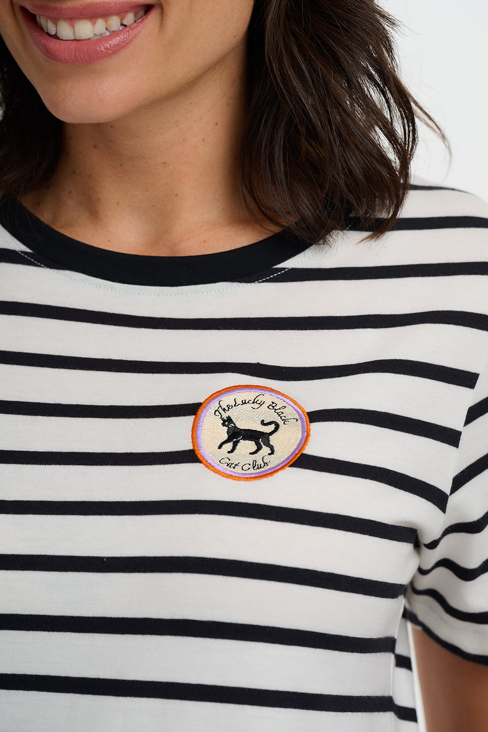 Person wearing a black and white striped shirt with a circular patch featuring a dog logo.