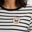 Person wearing a black and white striped shirt with a circular patch featuring a dog logo.