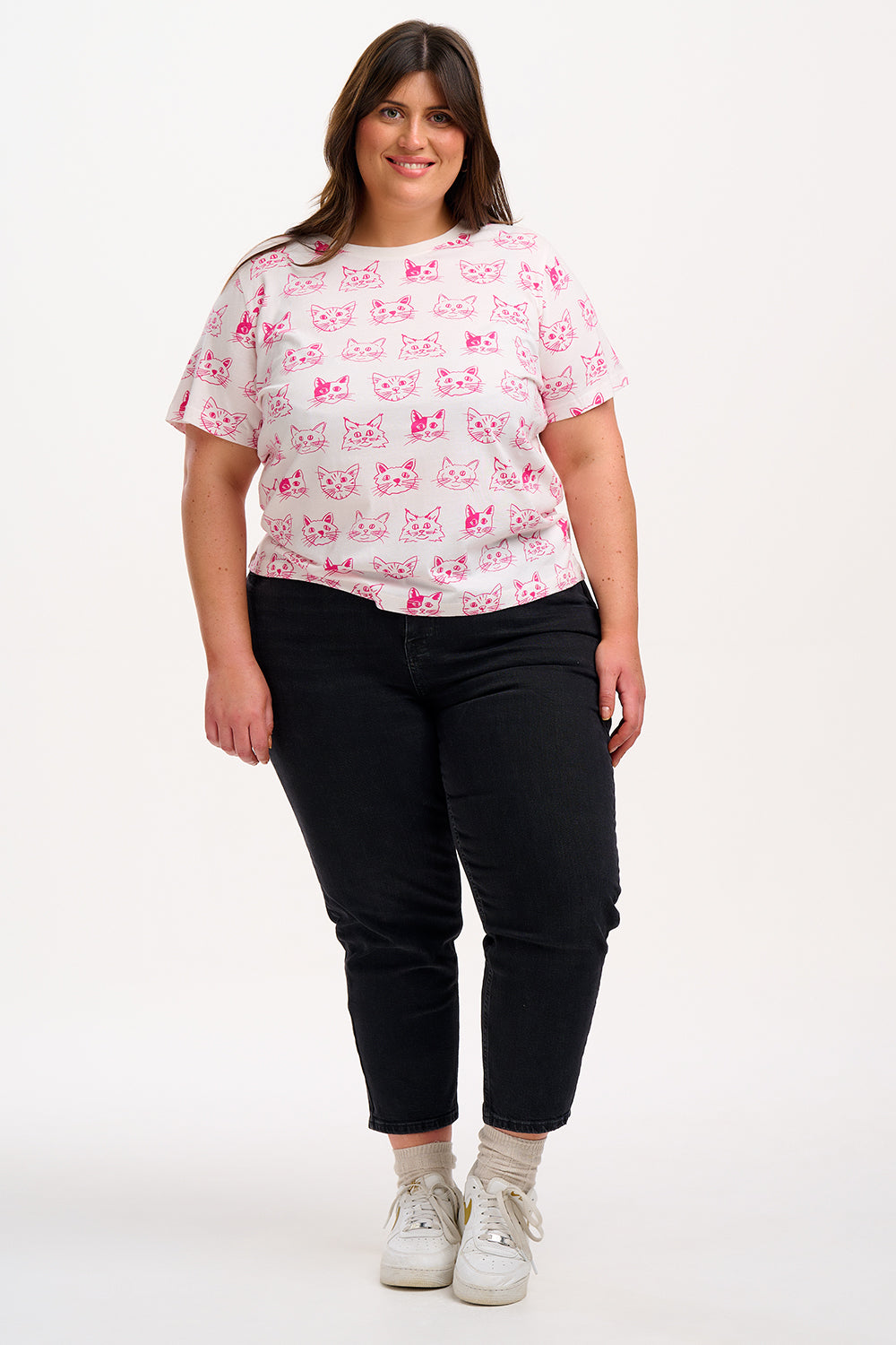 Woman wearing a white t-shirt with pink cat patterns.