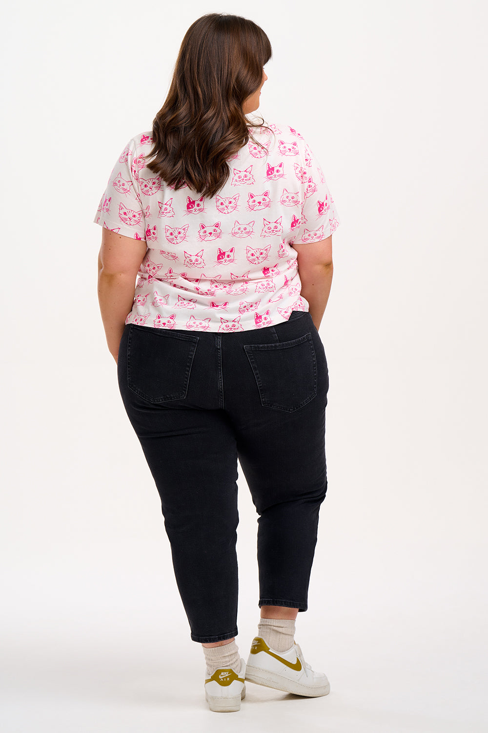 Woman wearing a white t-shirt with pink cat patterns.