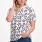 Woman wearing a white t-shirt with black star pattern and blue jeans on a white background