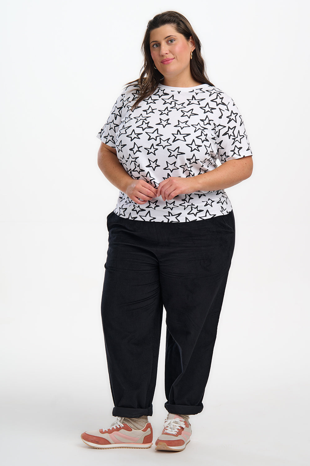 Woman wearing a white t-shirt with black patterns and black pants on a white background