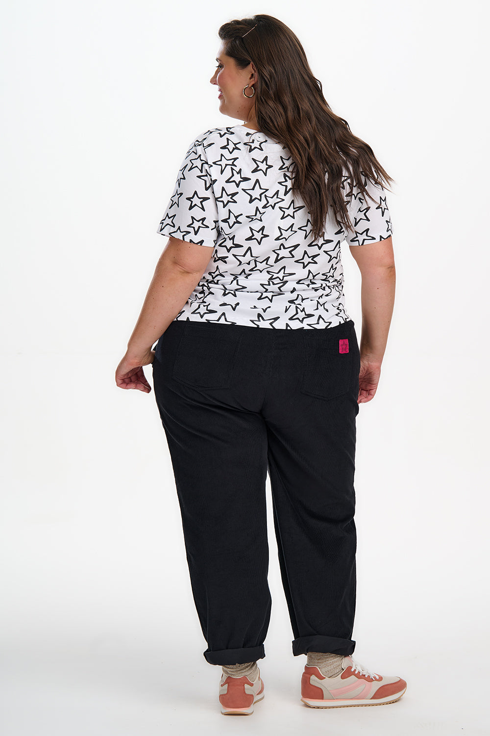Person wearing a white shirt with black star pattern and black pants on a white background