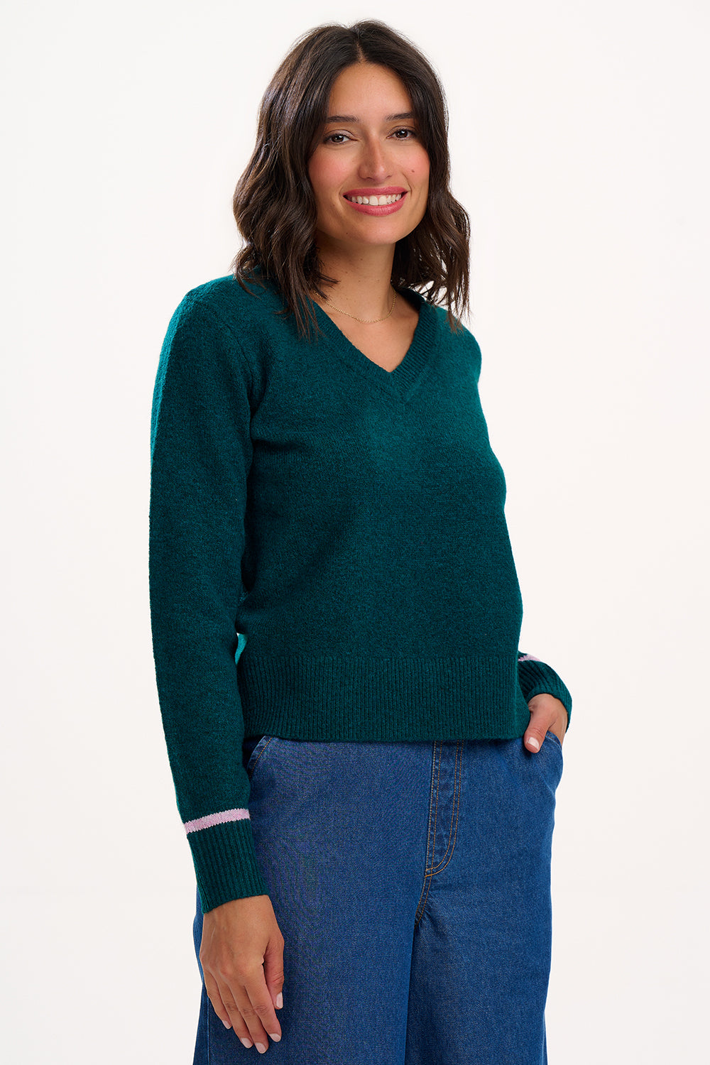 Woman wearing a green sweater and blue jeans on a white background