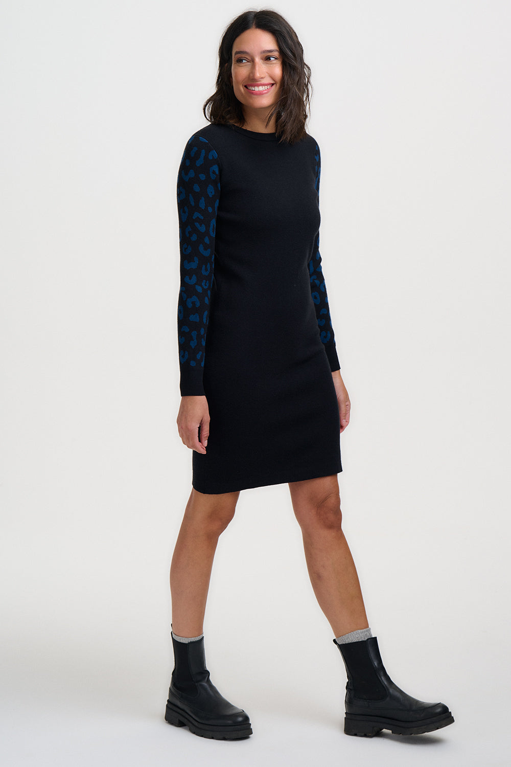 Woman wearing a black dress with blue patterned sleeves on a white background