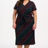 A model wearing a midi-length jersey dress with a V-neck, tie belt, and undulating multicoloured wave print. The dress is primarily black with red, pink, green, blue, and orange patterns.