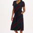A model wearing a midi-length jersey dress with a V-neck, tie belt, and undulating multicoloured wave print. The dress is primarily black with red, pink, green, blue, and orange patterns.