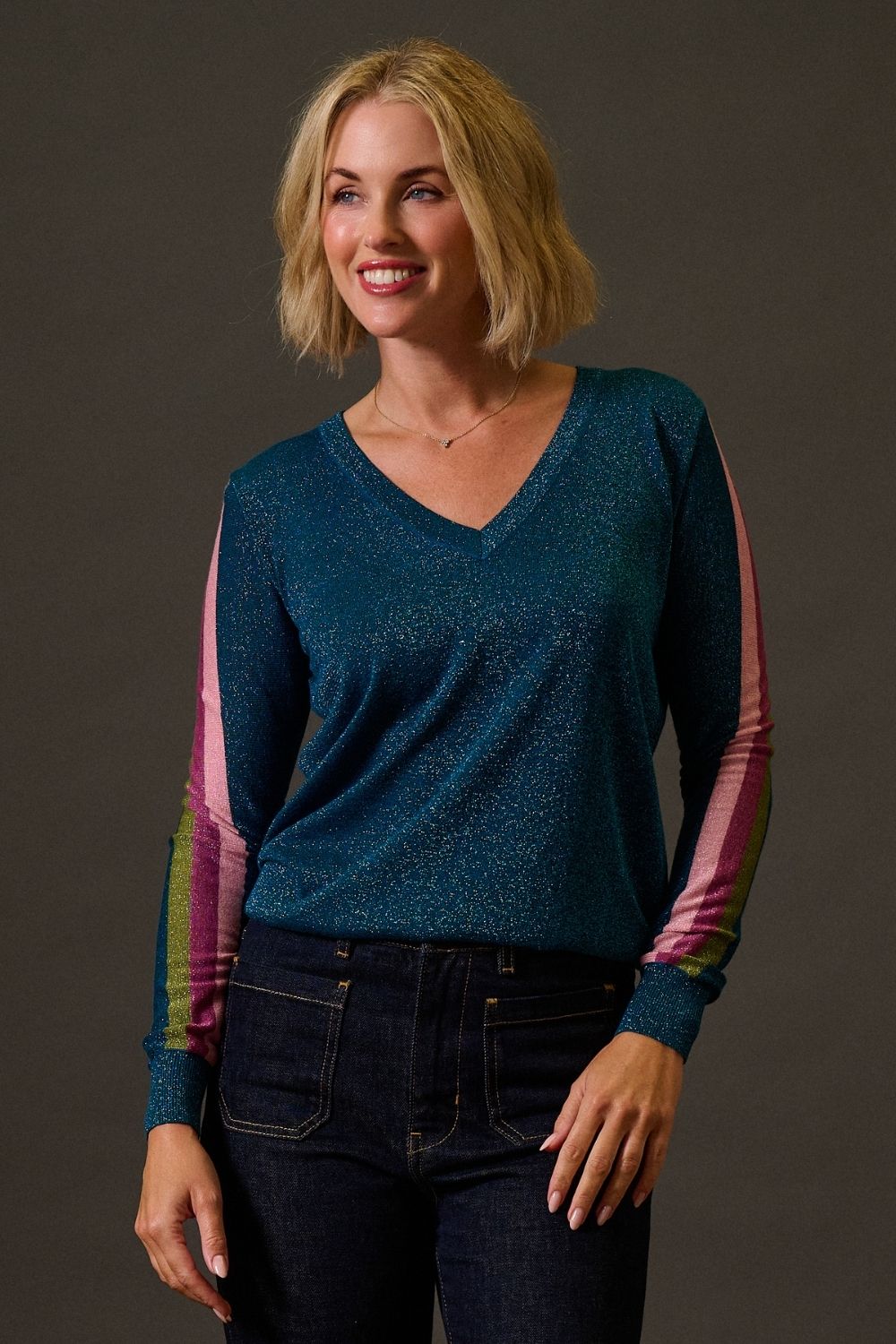 Woman wearing a blue sweater with colorful sleeves against a brown background