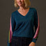 Woman wearing a blue sweater with colorful sleeves against a brown background