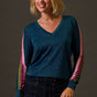 Woman wearing a blue sweater with colorful sleeves against a brown background