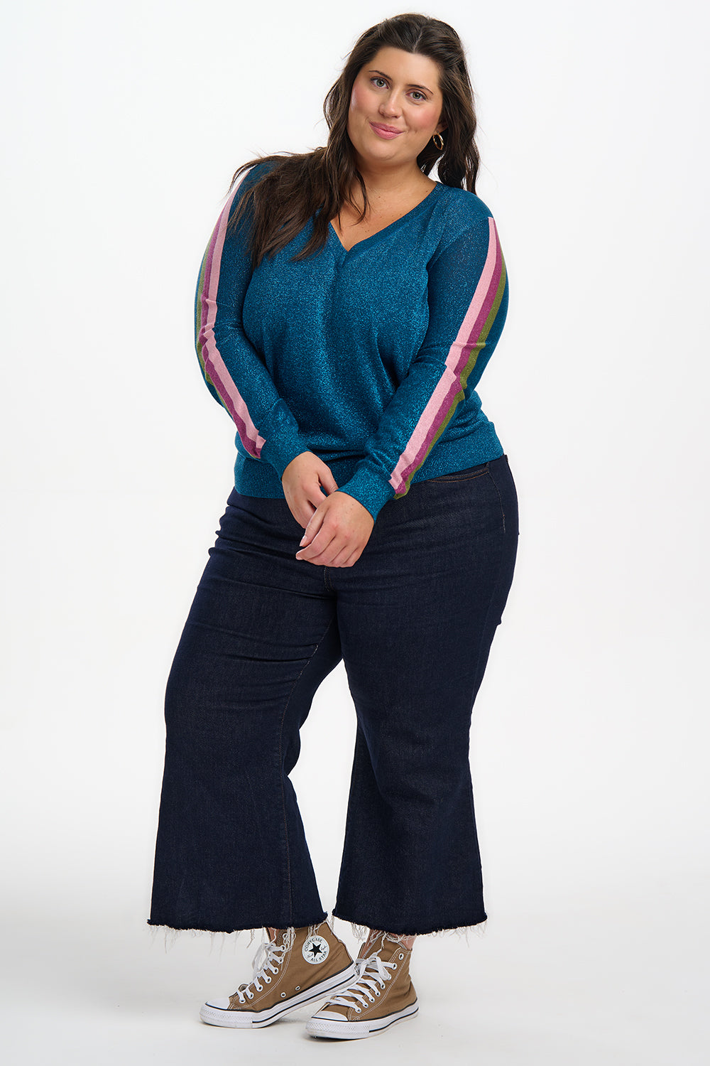Woman wearing a blue top with colorful sleeves and black pants on a white background