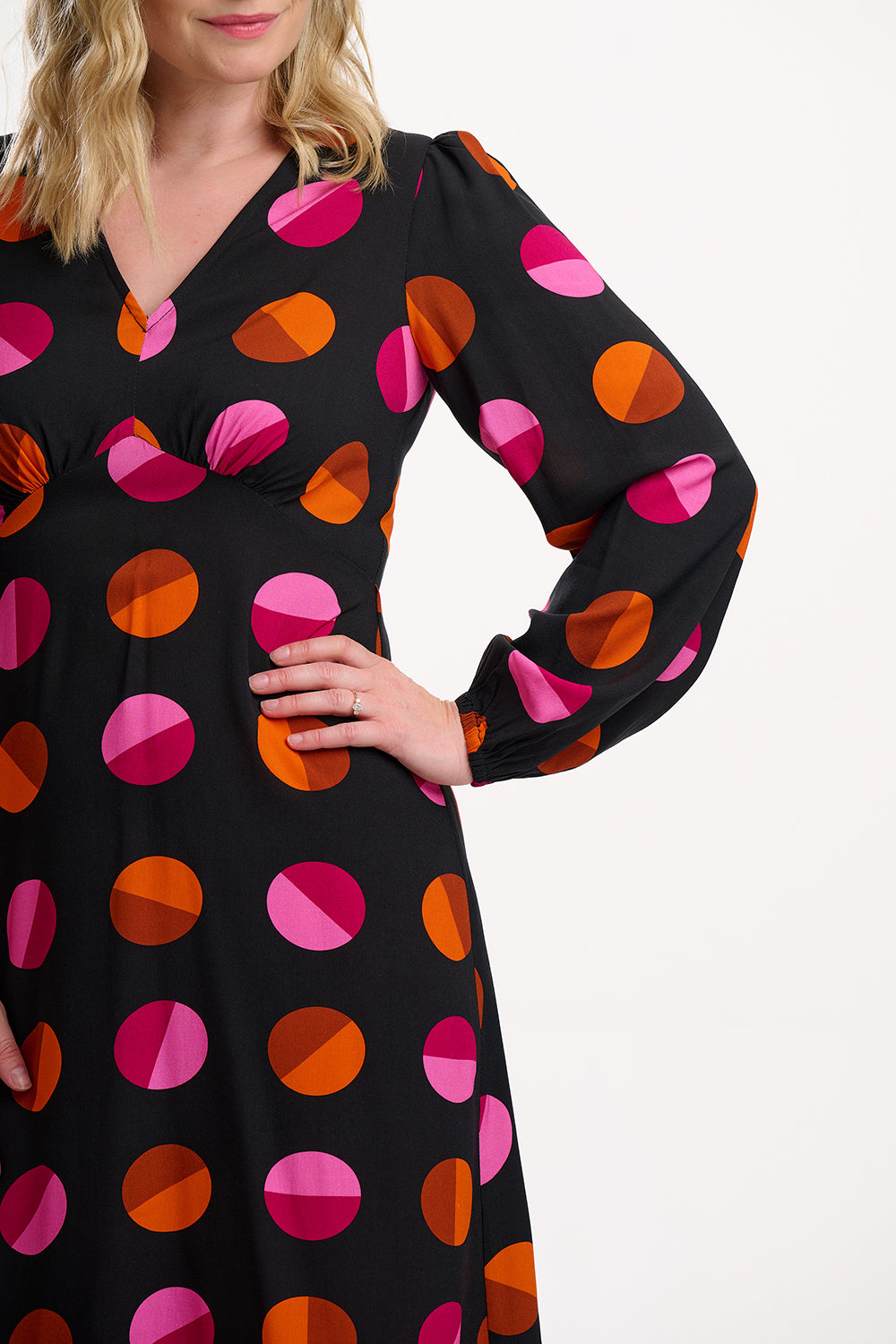 Woman wearing a black dress with pink and orange geometric pattern on a white background