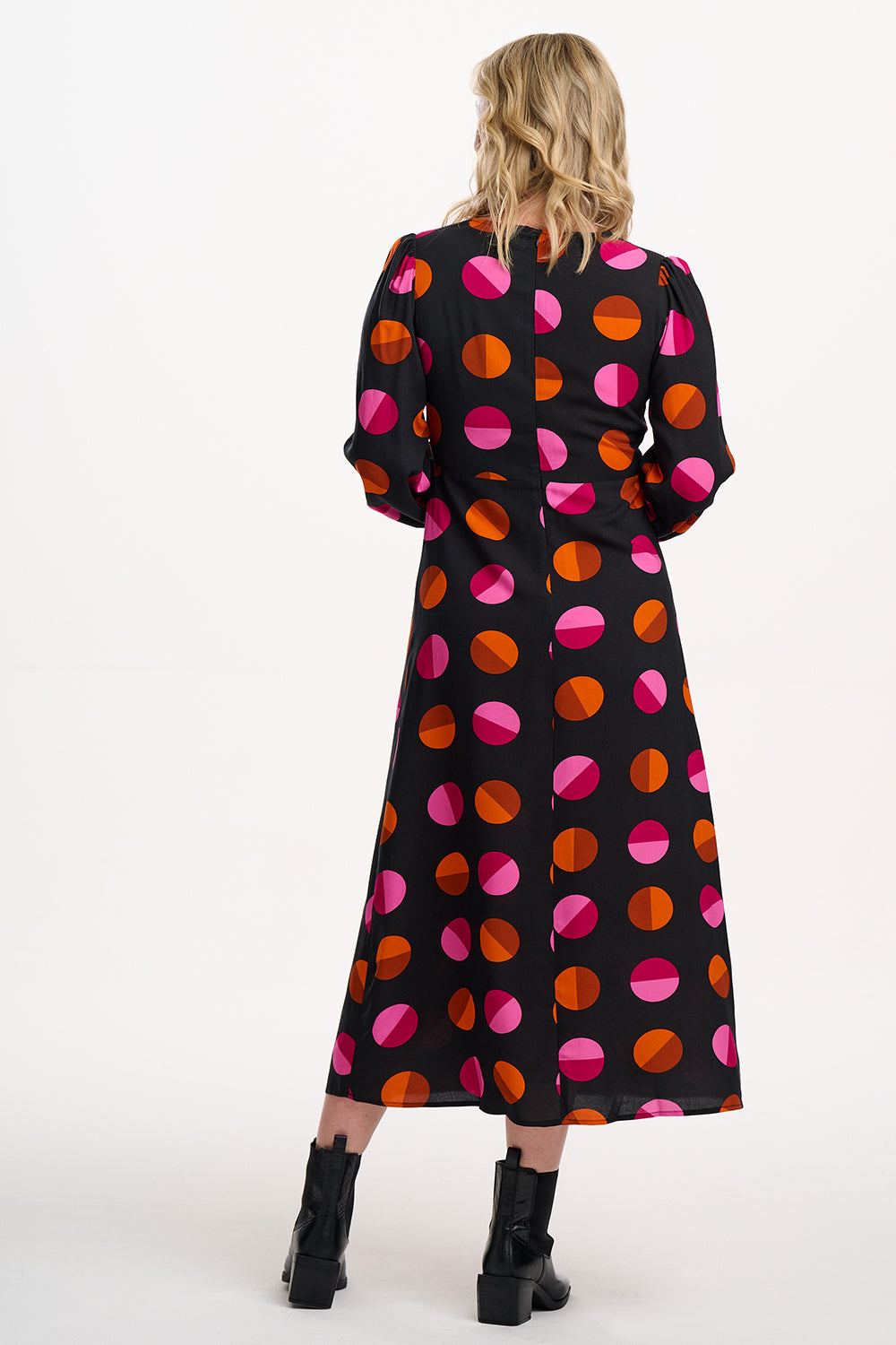 Woman wearing a black dress with colorful polka dot pattern on a white background