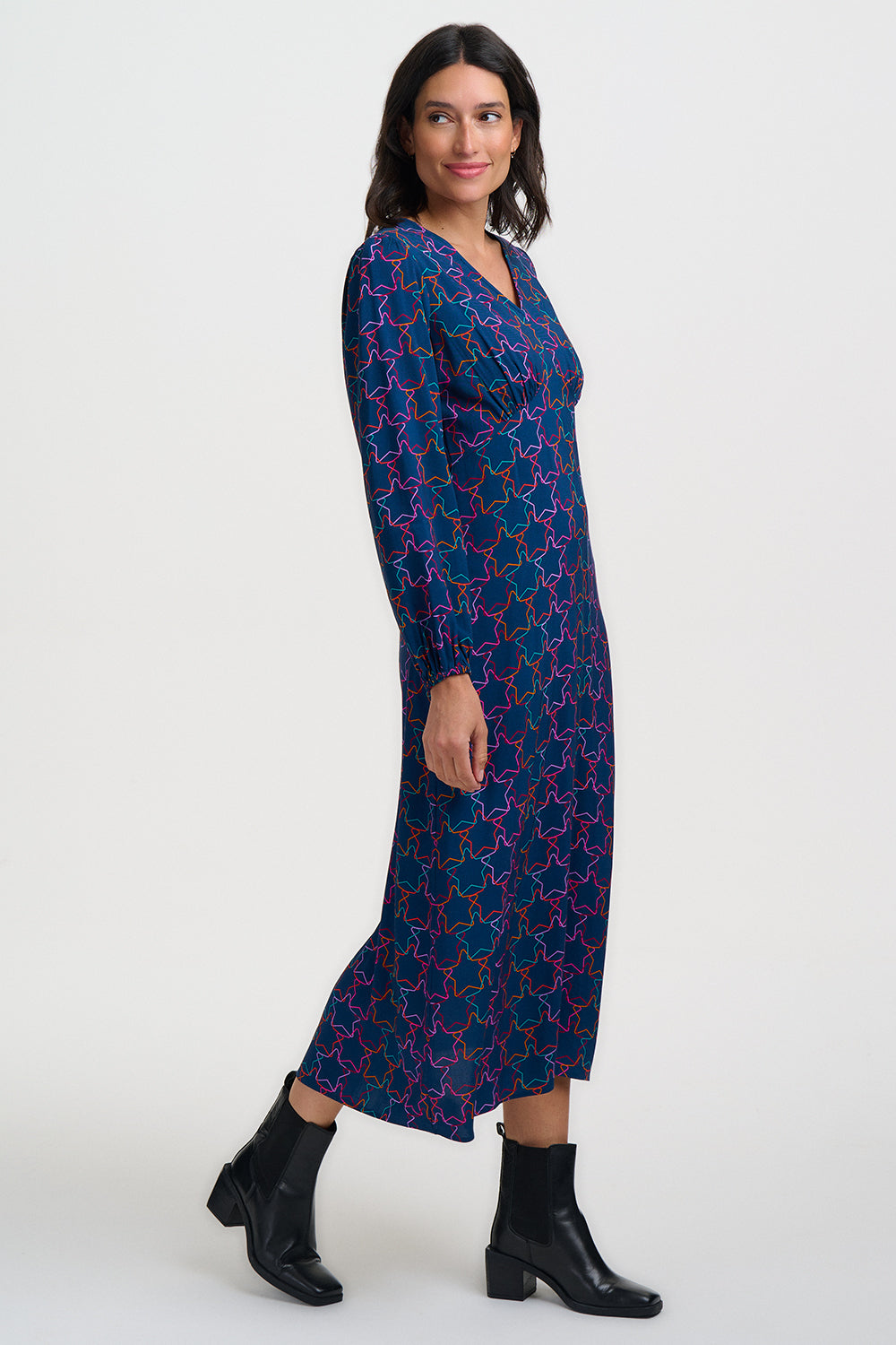 Woman wearing a blue patterned dress with black boots on a white background