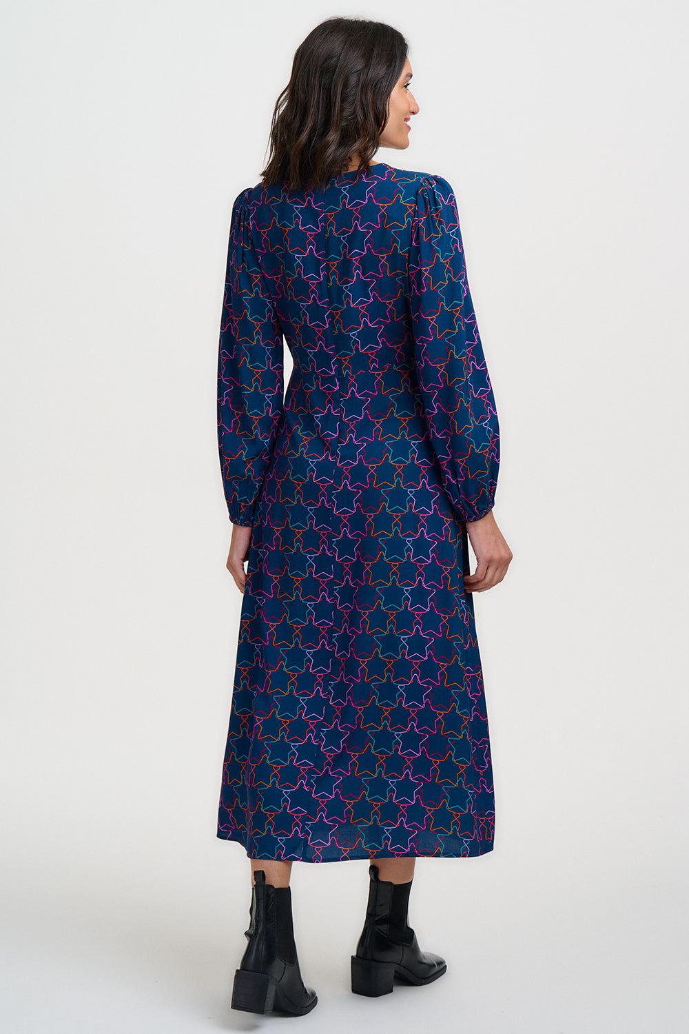 Woman wearing a long, dark blue dress with a pattern on a white background