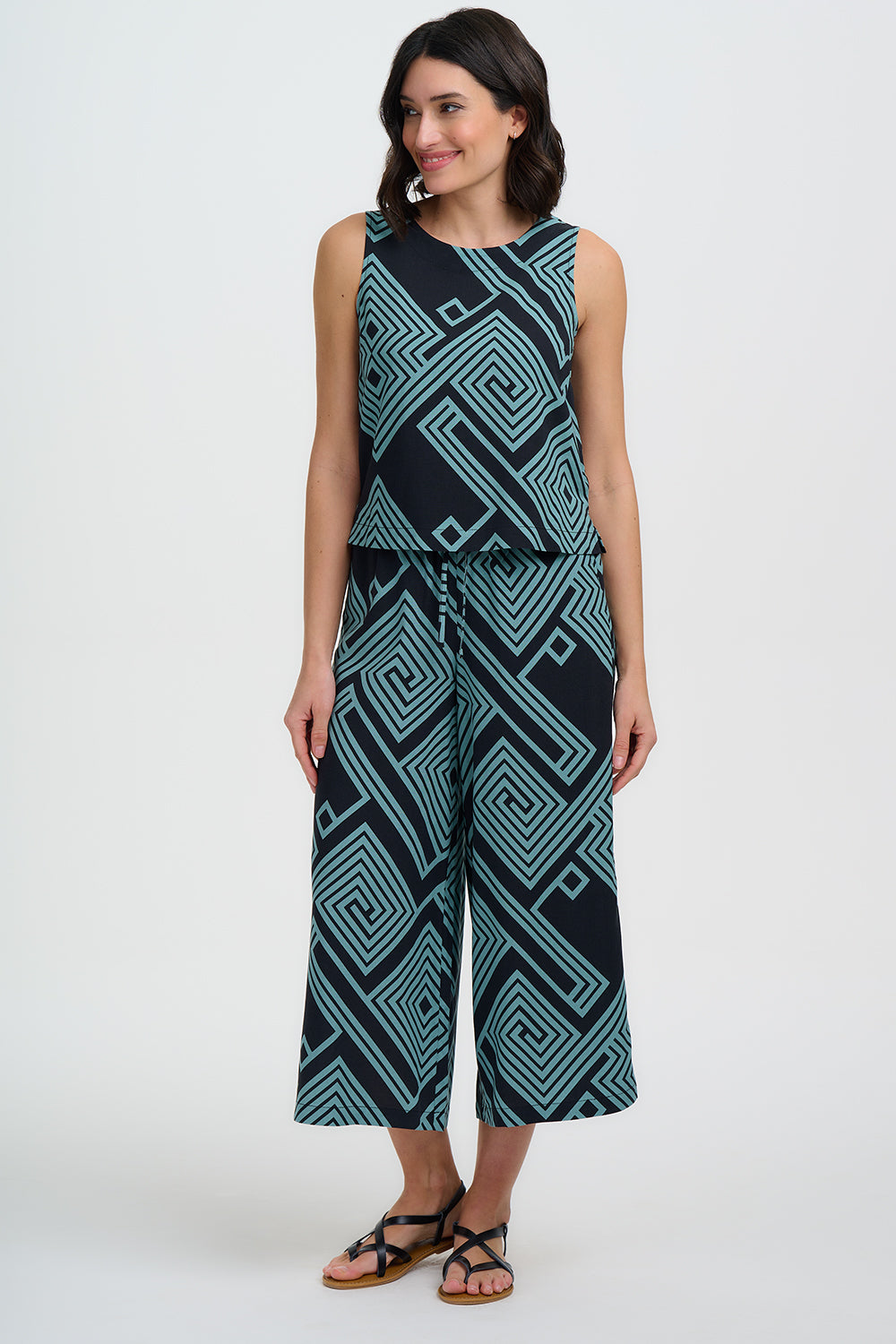 Woman wearing a sleeveless jumpsuit with geometric pattern on a white background