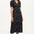 A model wearing a mid-length black dress with a V-neck and short-shirred sleeves, adorned with a multicolor floral and star print.