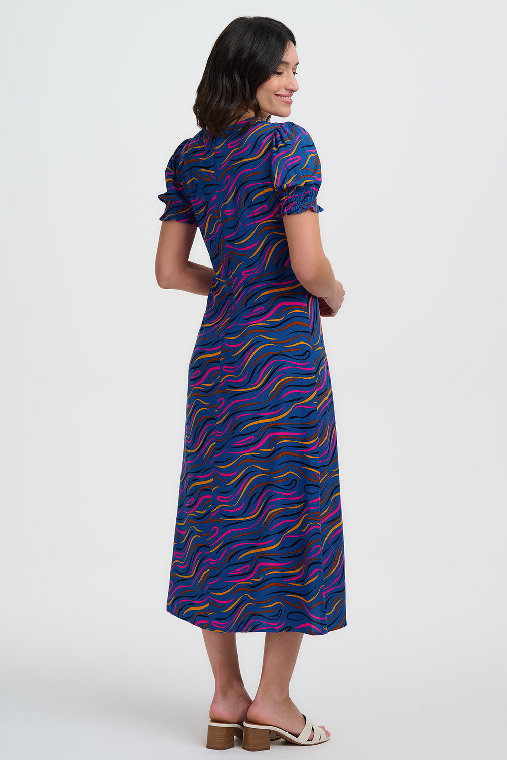 Woman wearing a blue dress with colorful patterns on a white background