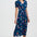 Woman wearing a navy dress with colorful floral and bird pattern on a white background