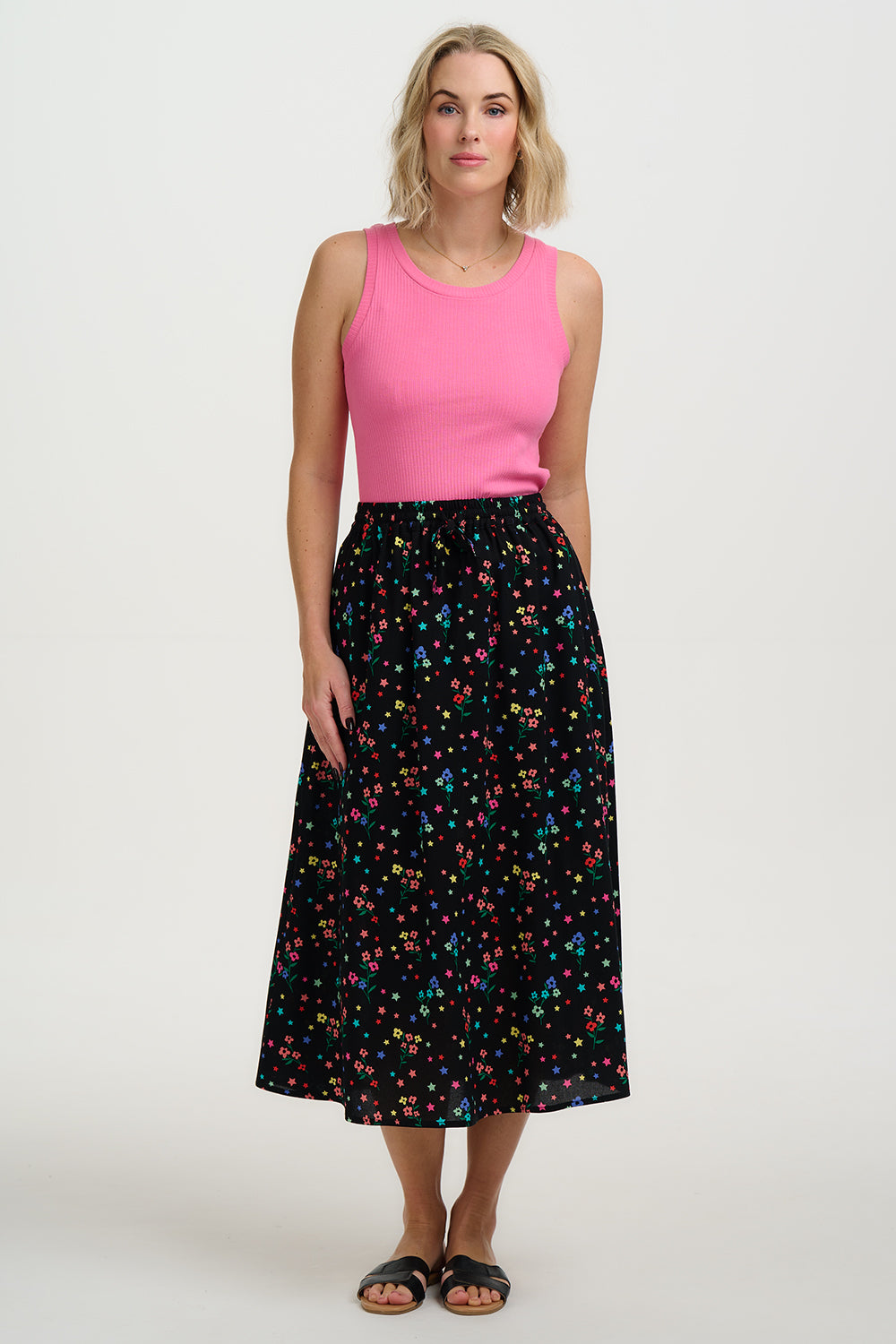 Woman wearing a pink top and black floral skirt on a white background