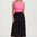 Woman wearing a pink top and black floral skirt on a white background
