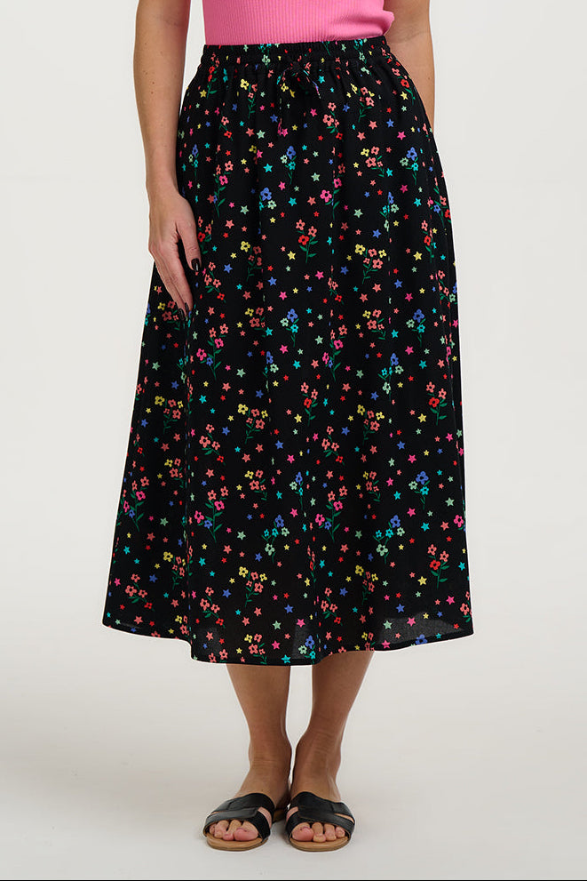 Woman wearing a pink top and black floral skirt on a white background