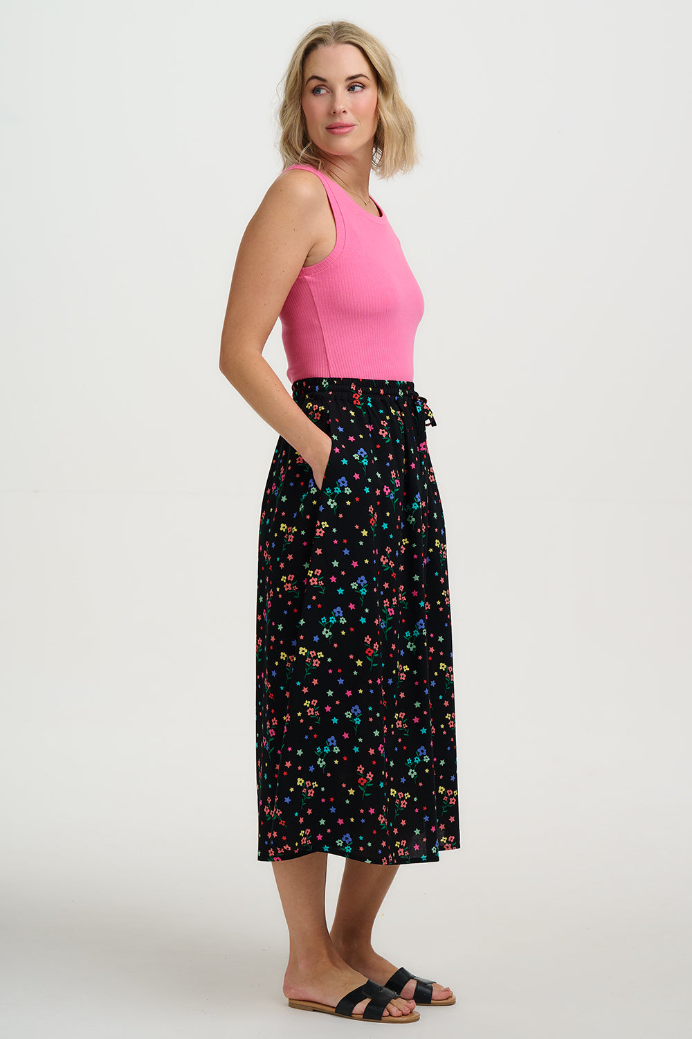 Woman wearing a pink top and black floral skirt on a white background