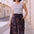 Woman wearing a striped tank top and patterned skirt standing on a street.