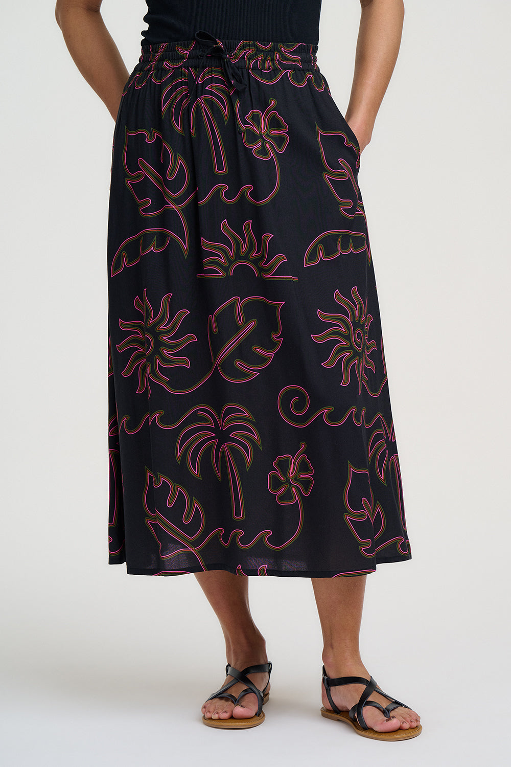 Person wearing a black skirt with red floral pattern on a white background