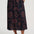 Person wearing a black skirt with red floral pattern on a white background