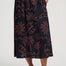 Person wearing a black skirt with red floral pattern on a white background