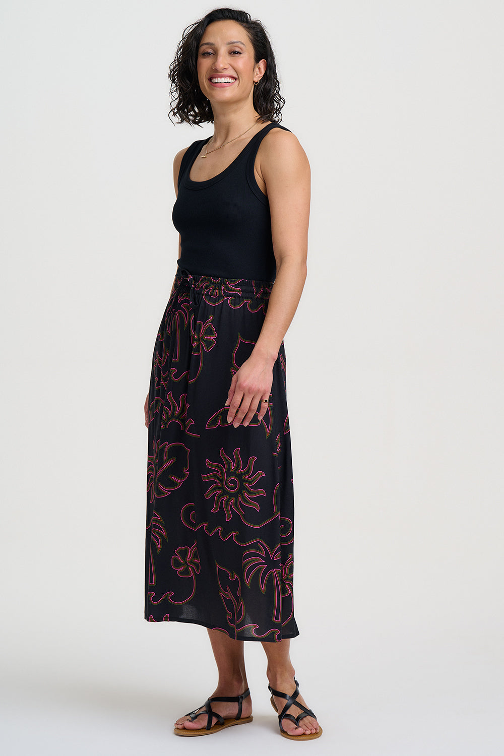 Woman wearing a black tank top and patterned skirt on a white background
