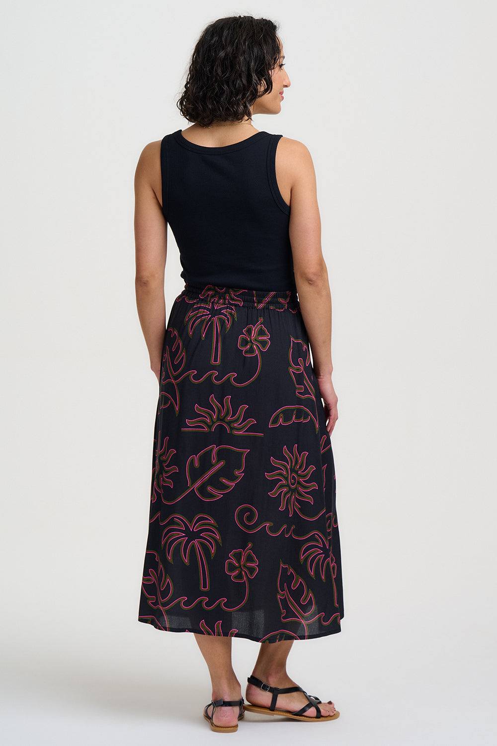 Woman wearing a black dress with pink floral patterns on a white background