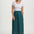 Woman wearing a white top and teal patterned skirt on a white background