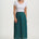 Woman wearing a white top and teal patterned skirt on a white background