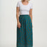 Woman wearing a white top and teal patterned skirt on a white background