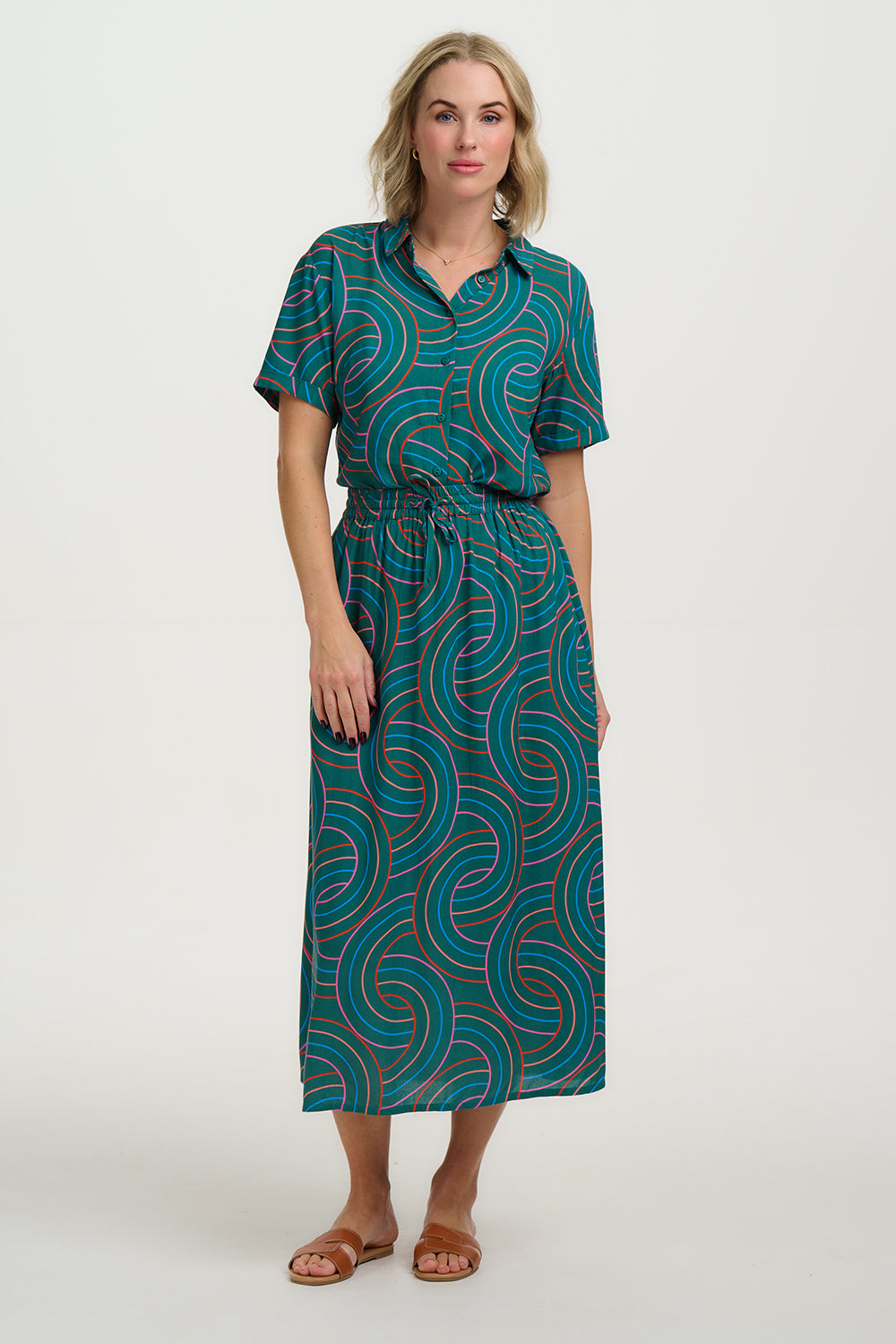 Woman wearing a teal patterned dress on a white background