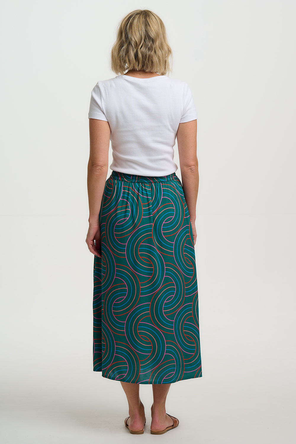 Woman wearing a white t-shirt and teal patterned skirt on a white background
