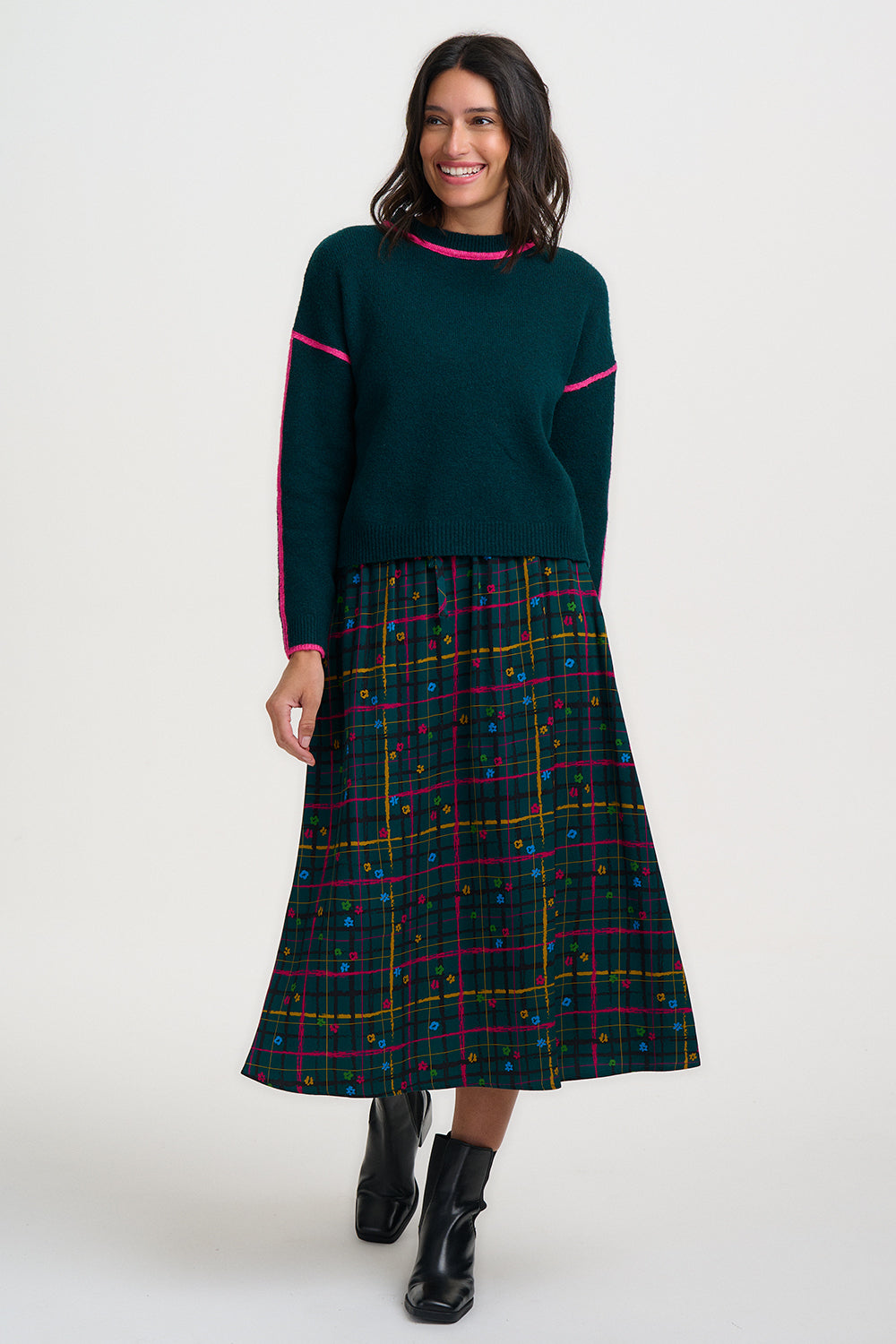 Woman wearing a green sweater and plaid skirt on a white background