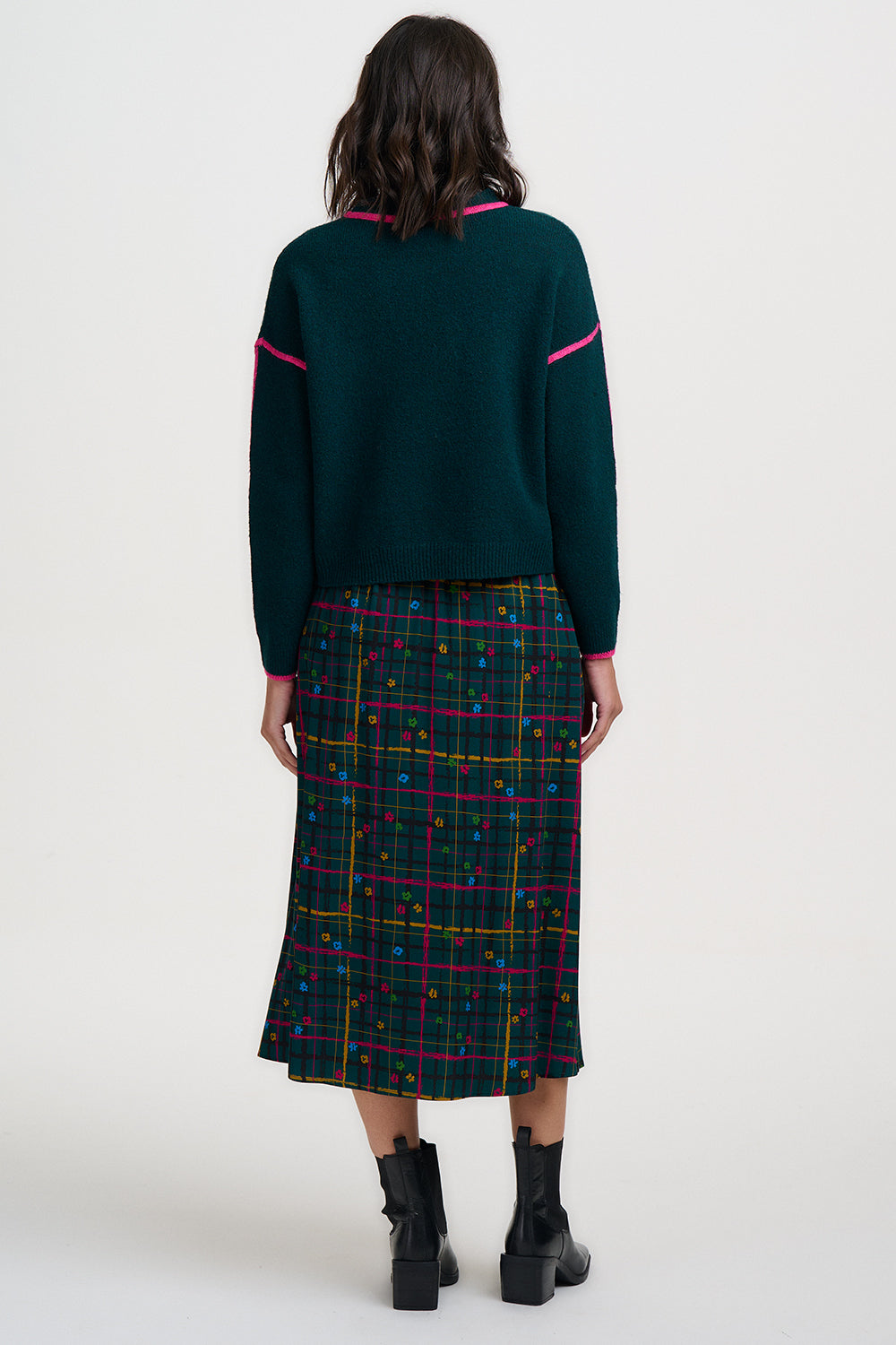 Person wearing a green sweater and plaid skirt on a white background