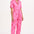 A woman modeling a short-sleeved pink boilersuit with a floral star pattern and a collar.