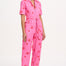 A woman modeling a short-sleeved pink boilersuit with a floral star pattern and a collar.