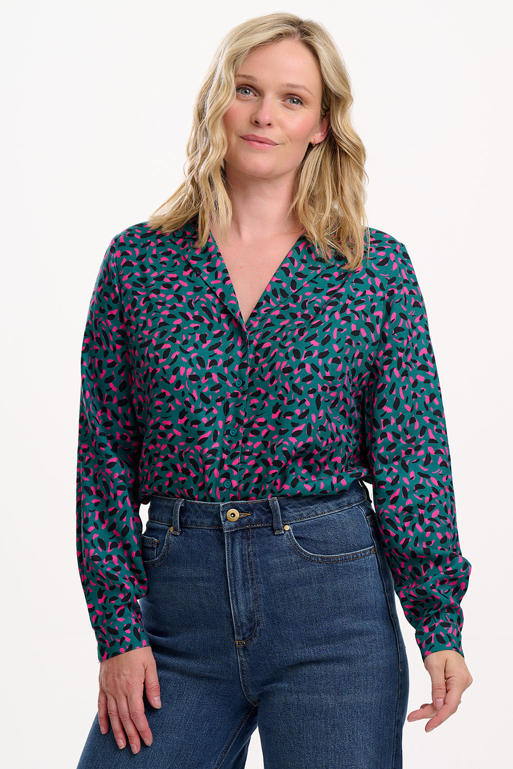 Woman wearing a patterned blouse and jeans on a white background