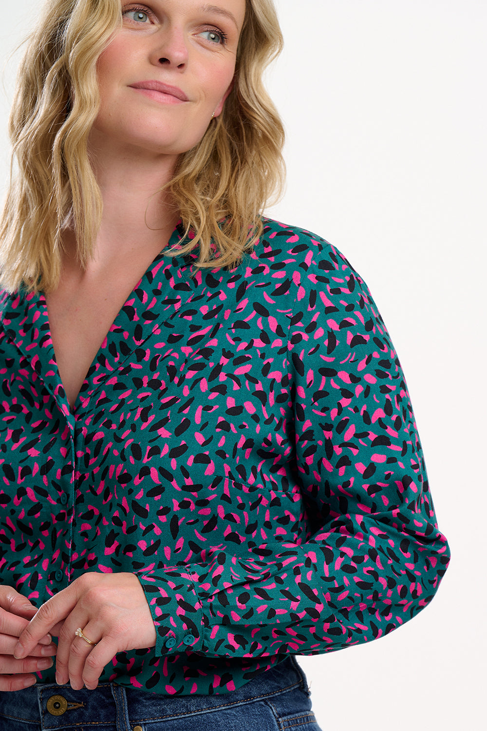 Woman wearing a green blouse with pink abstract pattern on a white background