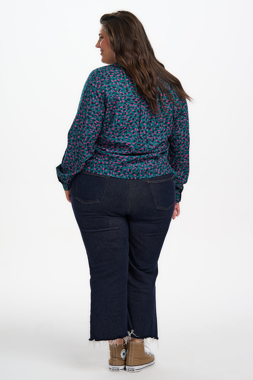 Person wearing a floral blouse and dark pants on a white background
