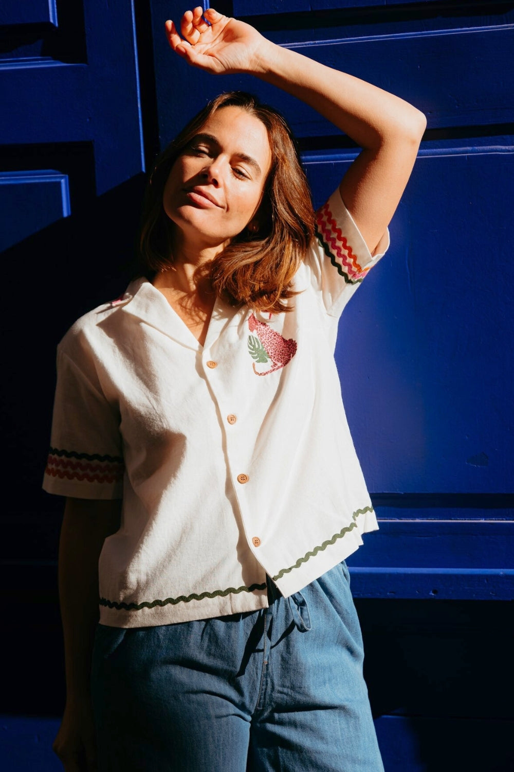 Woman wearing a white blouse with colorful trim against a blue background