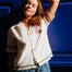 Woman wearing a white blouse with colorful trim against a blue background