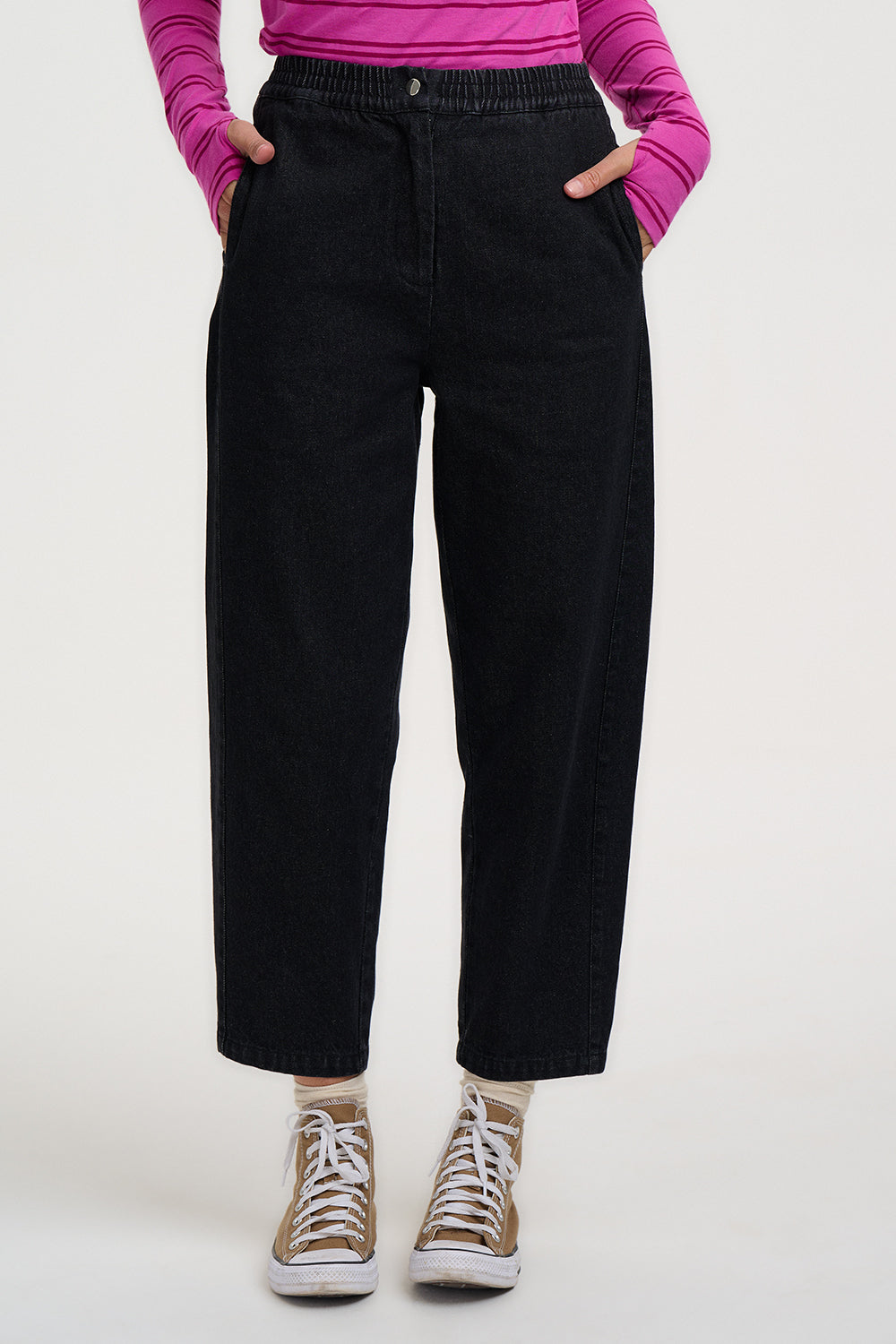 Person wearing black pants and a pink top on a white background