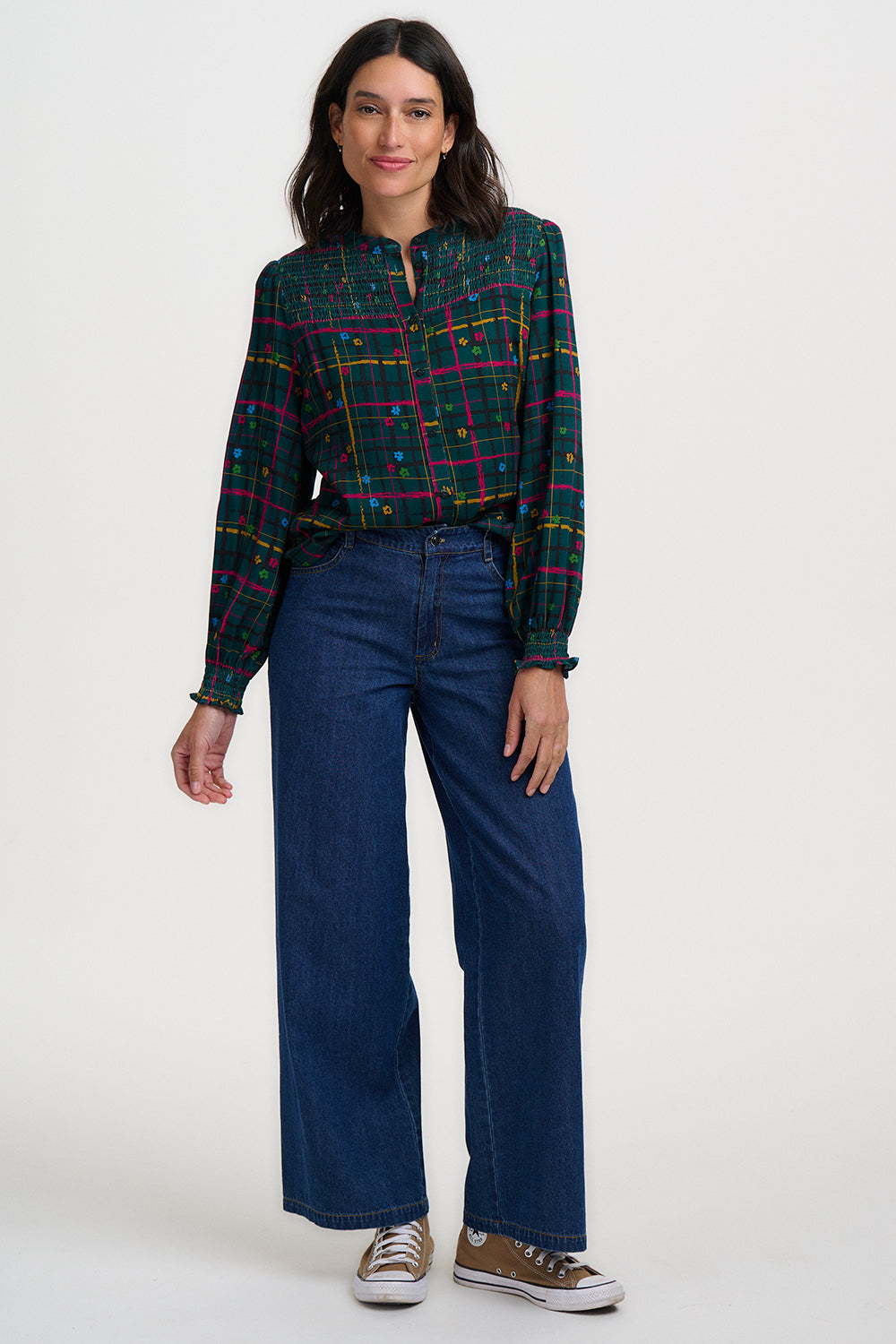 Woman wearing a plaid shirt and blue jeans on a white background
