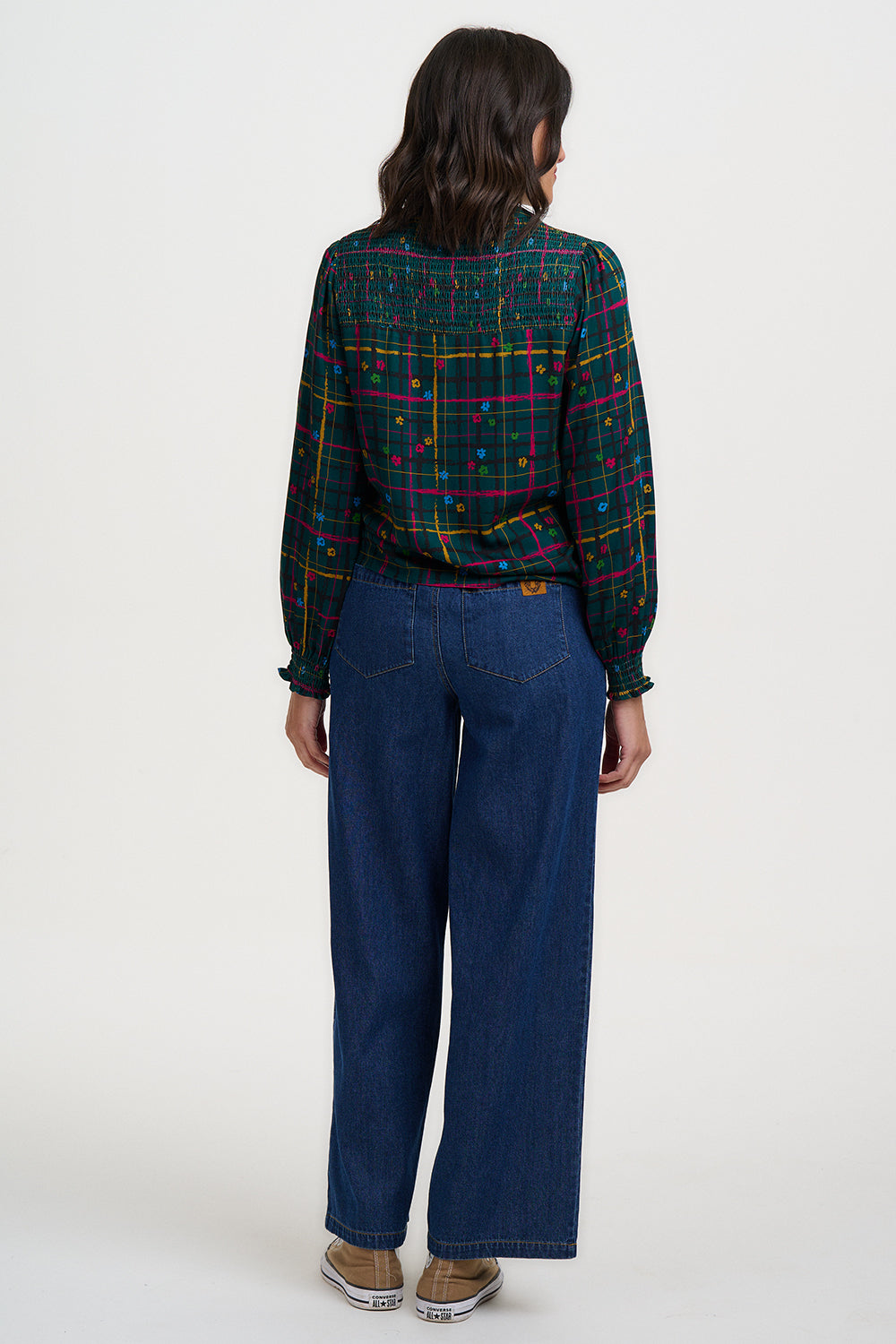 Person wearing a plaid shirt and blue jeans on a white background
